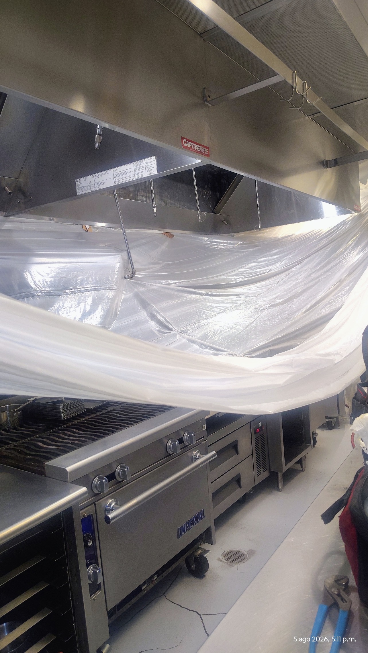 Commercial kitchen protected with plastic sheeting during hood cleaning